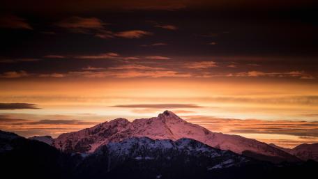 Majestic Winter Mountains Under Orange Sky wallpaper
