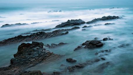 Serene Misty Waves Embracing Rocky Shores wallpaper