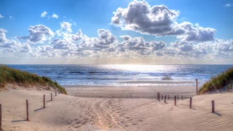 Serene Beach Landscape Under Fluffy Clouds wallpaper