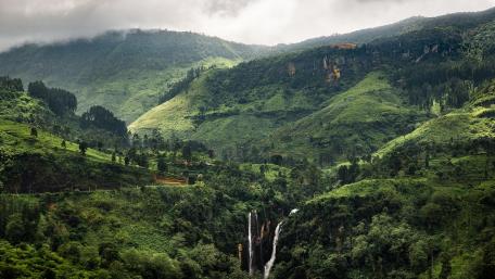 Serene Waterfall Amidst Lush Green Hills wallpaper