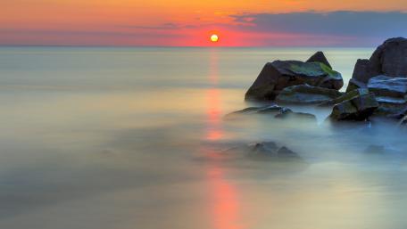 Sunset Serenity over Misty Waters and Boulders wallpaper