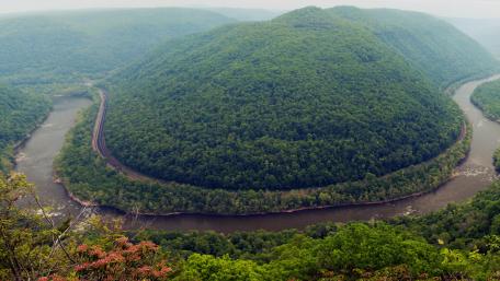 Serene River Bend Amidst Lush Mountains wallpaper