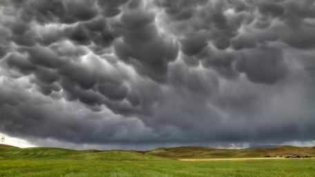 Dramatic Thunderclouds Over Rolling Hills wallpaper