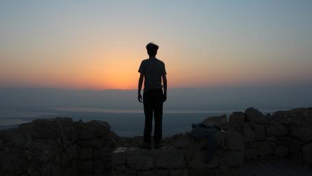 Man standing on white stones looking in sea wallpaper
