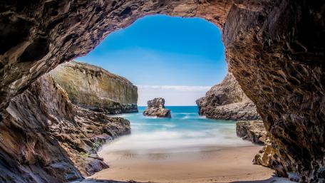Serene Cove Through Rocky Archway wallpaper
