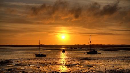 Golden Sunset Over Tranquil Lake and Sailboats wallpaper