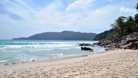Serene Beach Escape with Gentle Waves and Rocky Shores wallpaper