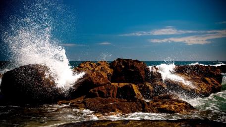 Majestic Sea Splashing Against Rocky Shoreline wallpaper