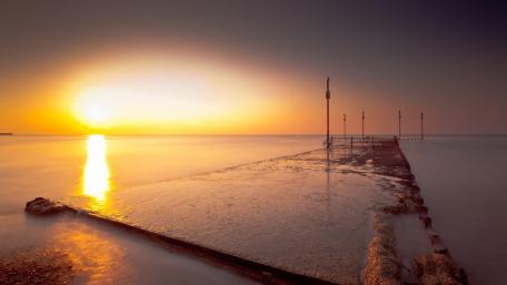 Serene Sunset Over the Pier and Ocean Waves wallpaper