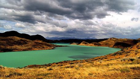 Serene River Landscape Under Dramatic Clouds wallpaper