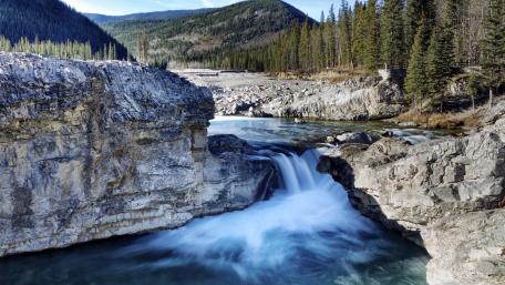 Serene Waterfall Amidst Majestic Mountains wallpaper