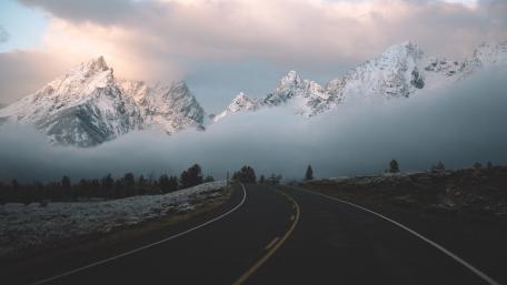 Serene Mountain Road Surrounded by Clouds and Fog wallpaper