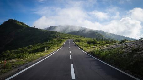 Winding Highway Through Lush Greenery and Misty Mountains wallpaper