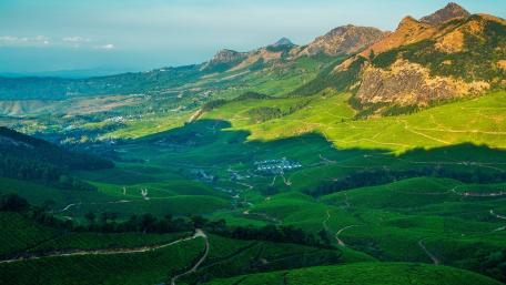 Lush Green Valley Under Mountain Peaks wallpaper