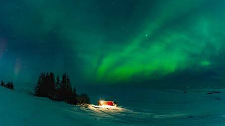 Enchanting Aurora Borealis Over Winter Cottage wallpaper