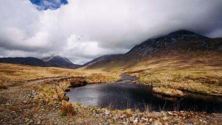 Serene Highland River Under Cloudy Skies wallpaper