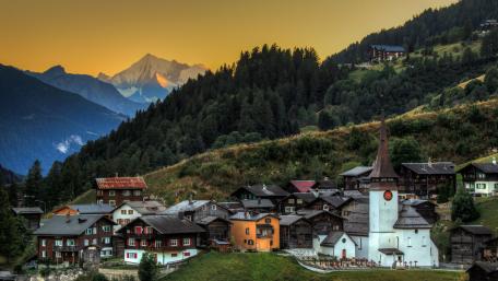 Serene Village Amidst Alpine Majesty wallpaper