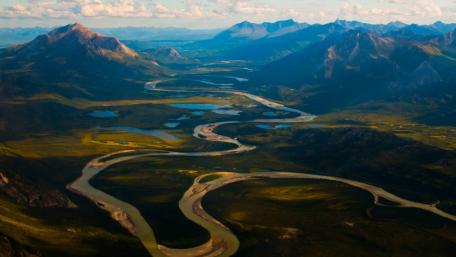 Serene River Meandering Through Majestic Mountains wallpaper
