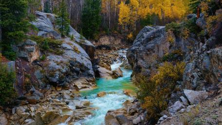 Serene River Flowing Through Rocky Landscape wallpaper