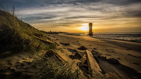 Tranquil Sunset at the Lighthouse Over Beach Sands wallpaper