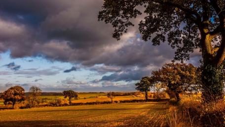 Serene Countryside Under Dramatic Clouds wallpaper