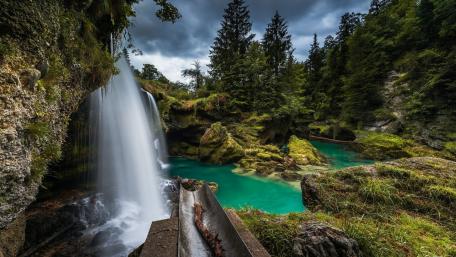 Majestic Waterfall in Tranquil Forest Setting wallpaper