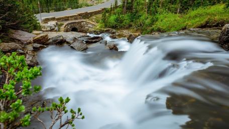 Serene Waterfall Flowing Amidst Lush Greenery wallpaper