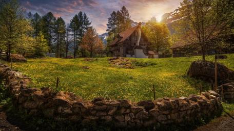 Serene Cottage Amidst Blossom Fields and Mountains wallpaper