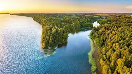 Tranquil River at Sunset Overlooking Lush Greenery wallpaper