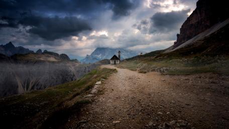 Serene Cottage Amidst Majestic Mountains wallpaper
