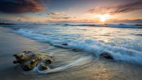 Serene Beach Sunset Over Gentle Waves wallpaper