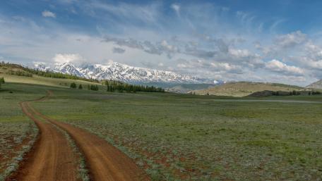 Serene Highland Road Under Majestic Mountains wallpaper