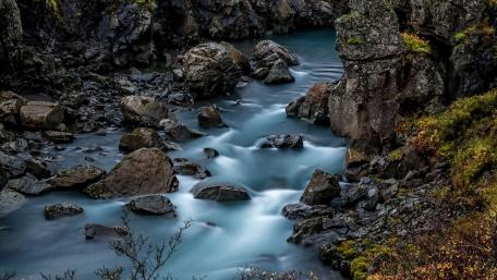 Serene River Flowing Through Rocky Landscape wallpaper