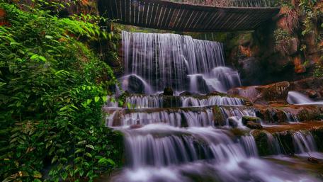 Tranquil Waterfall Beneath a Wooden Bridge wallpaper