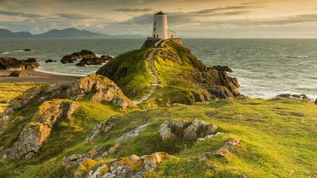 Lighthouse on a Coastal Hill at Sunset wallpaper