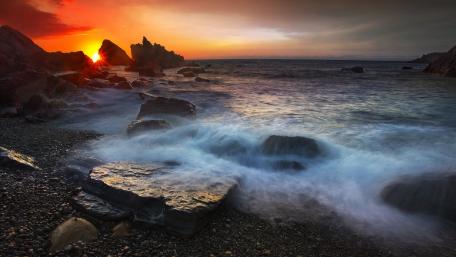 Serene Sunset Over Waves and Rocks wallpaper