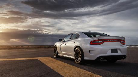 Sleek White Car Under Dramatic Clouds wallpaper
