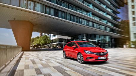 Dynamic Opel Astra in Urban Setting with Modern Architecture wallpaper