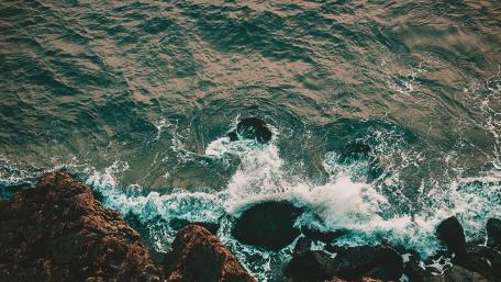 Serene Ocean Waves Embracing Rocky Shoreline wallpaper