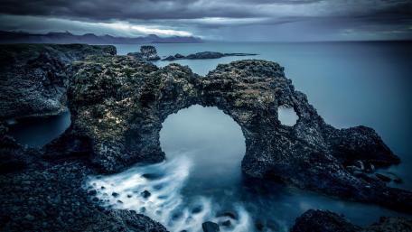 Mysterious Coastal Arch Under Cloudy Skies wallpaper