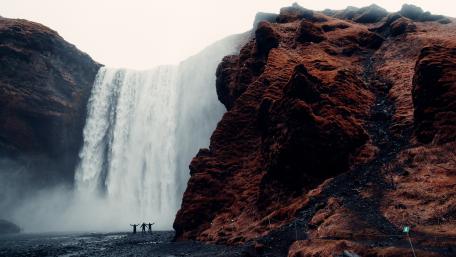 Waterfall Serenity with Majestic Cliffs and People Silhouettes wallpaper