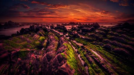 Vibrant Sunset Over Rocky Shoreline wallpaper