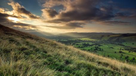 Serene Hillside Under Scattered Clouds wallpaper