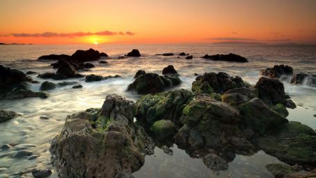 Serene Sunset Over Rocky Shoreline wallpaper