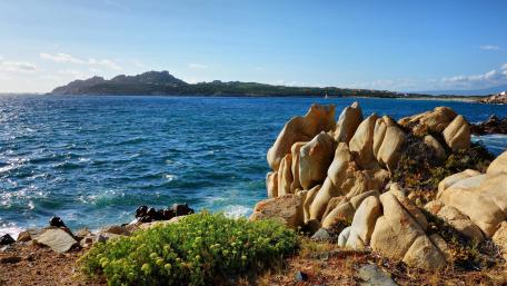 Serene Coastal Landscape with Turquoise Water and Rocky Shoreline wallpaper
