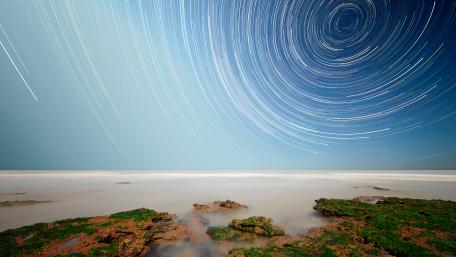Captivating Star Trails Over Serene Waters wallpaper