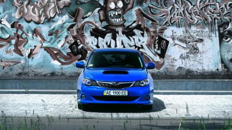 Bold Blue Subaru Against Urban Graffiti Wall wallpaper