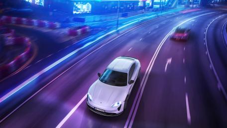 Porsche Taycan Speeding Through Neon Cityscape wallpaper