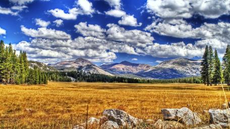 Majestic Mountain Landscape with Vibrant Clouds and Fields wallpaper