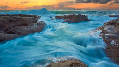 Serene Waves Crash Against Rocky Shoreline wallpaper